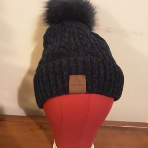 Dark blue lined winter hat with fluffy puff ball